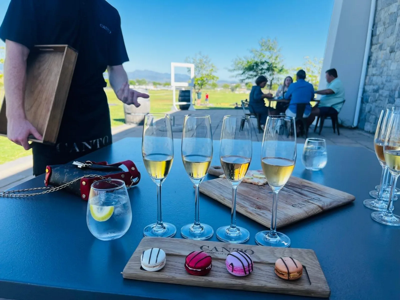 A staff member setting out sparkling wine and a macaron pairing board