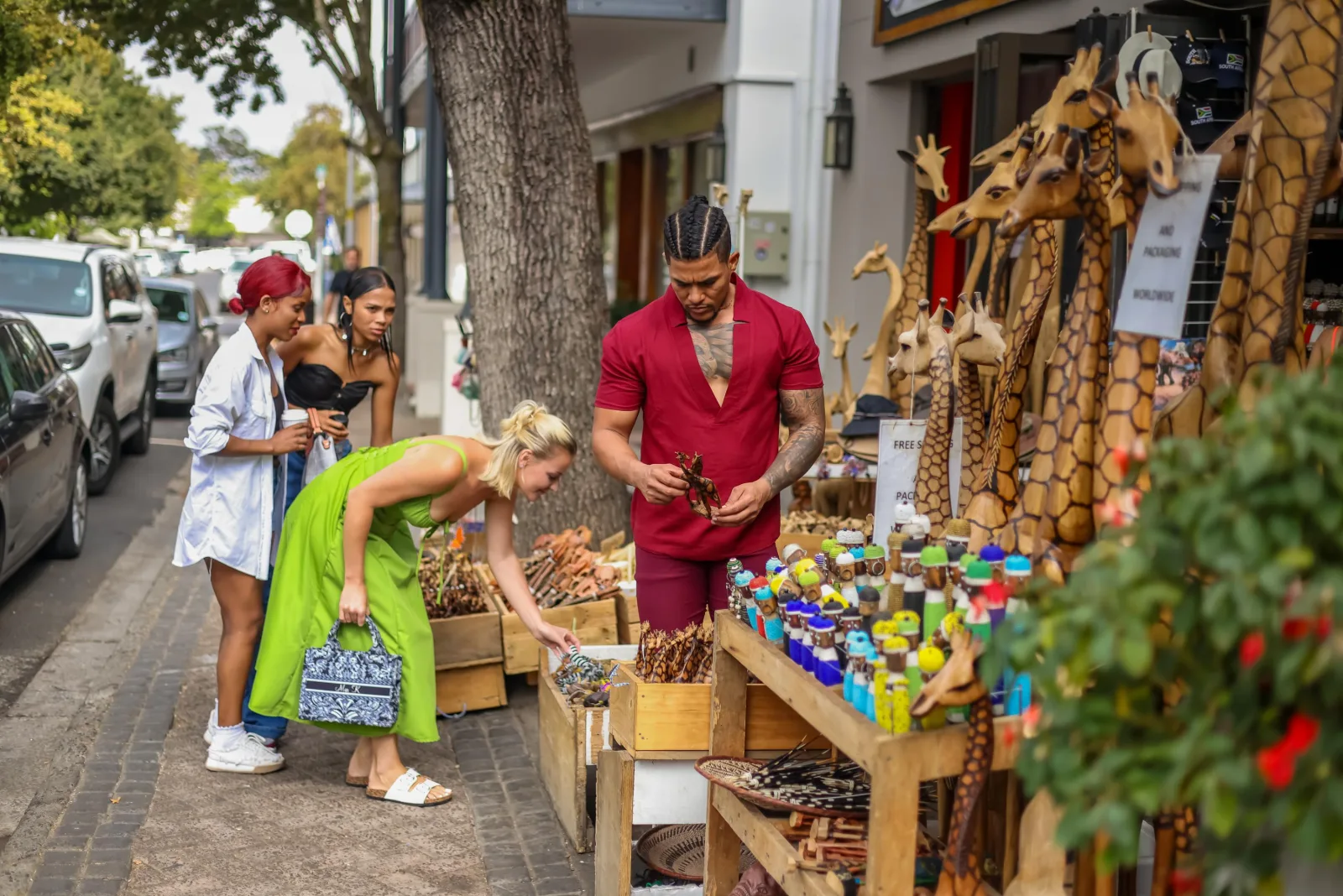 Shoppers at a pavement stall of carved wooden animals in Franschhoek
