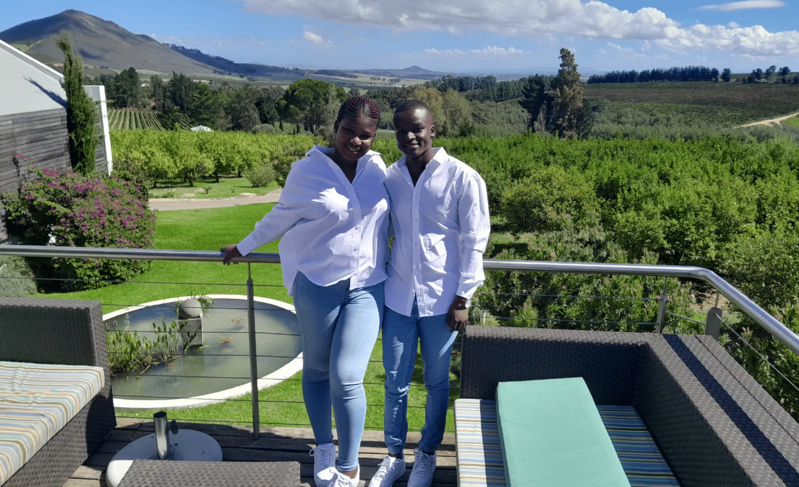 Two guests on an estate terrace with vineyards and mountains beyond