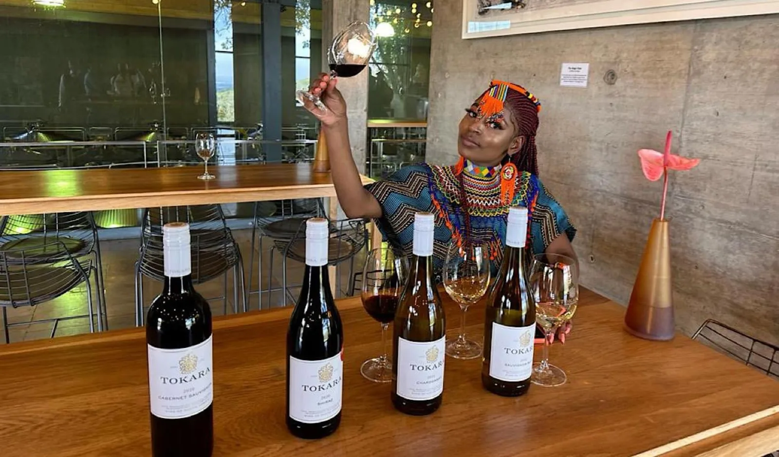 A guest raising a glass at the Tokara tasting bar beside a row of Tokara bottles