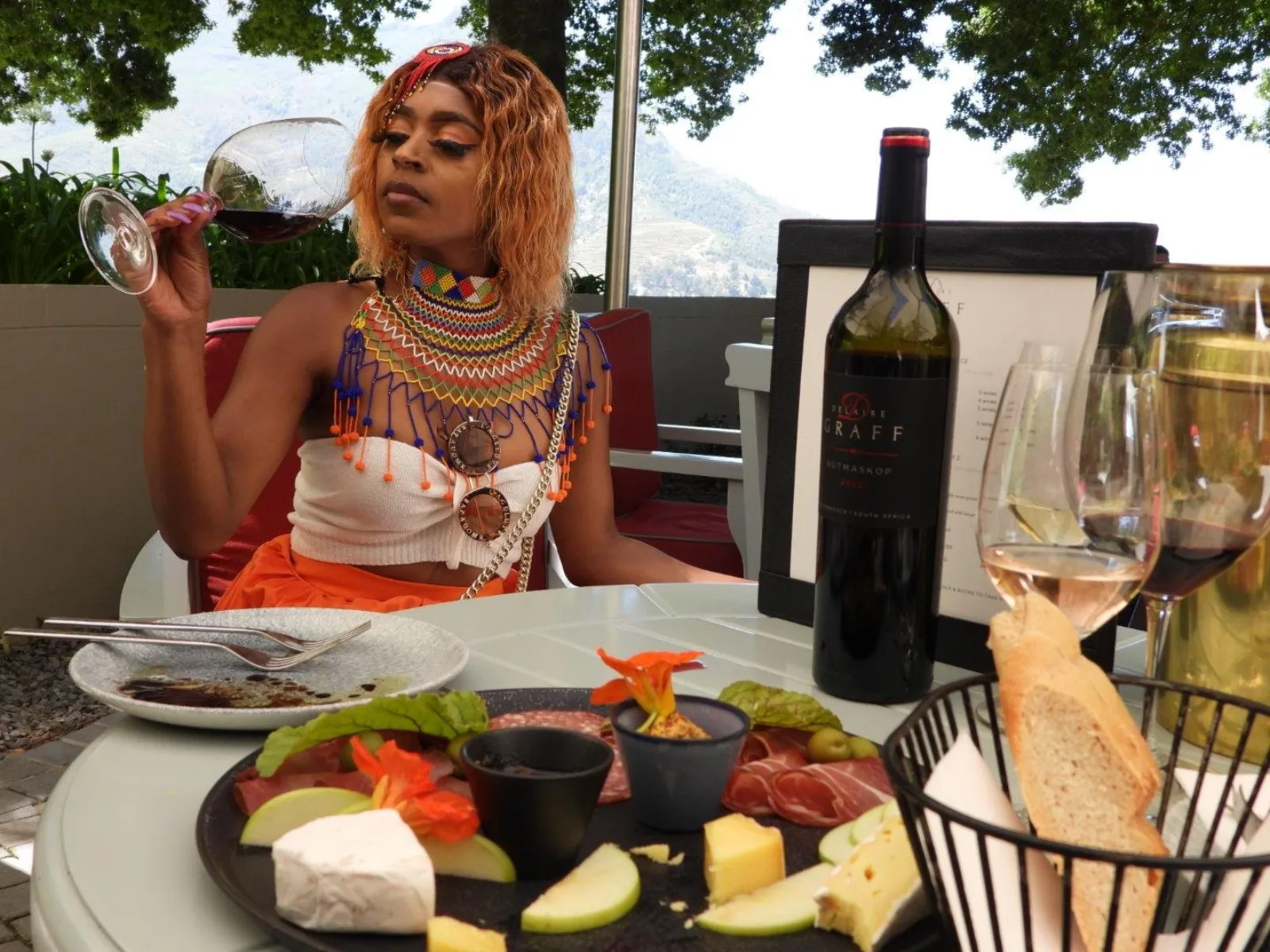 A wine and charcuterie board with an estate bottle and mountain views behind